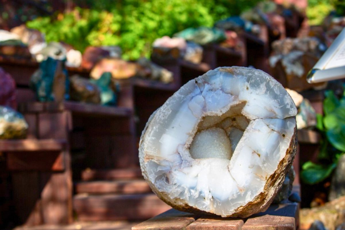 A large polished white agate geode crystal on display in an outdoor garden exhibition.