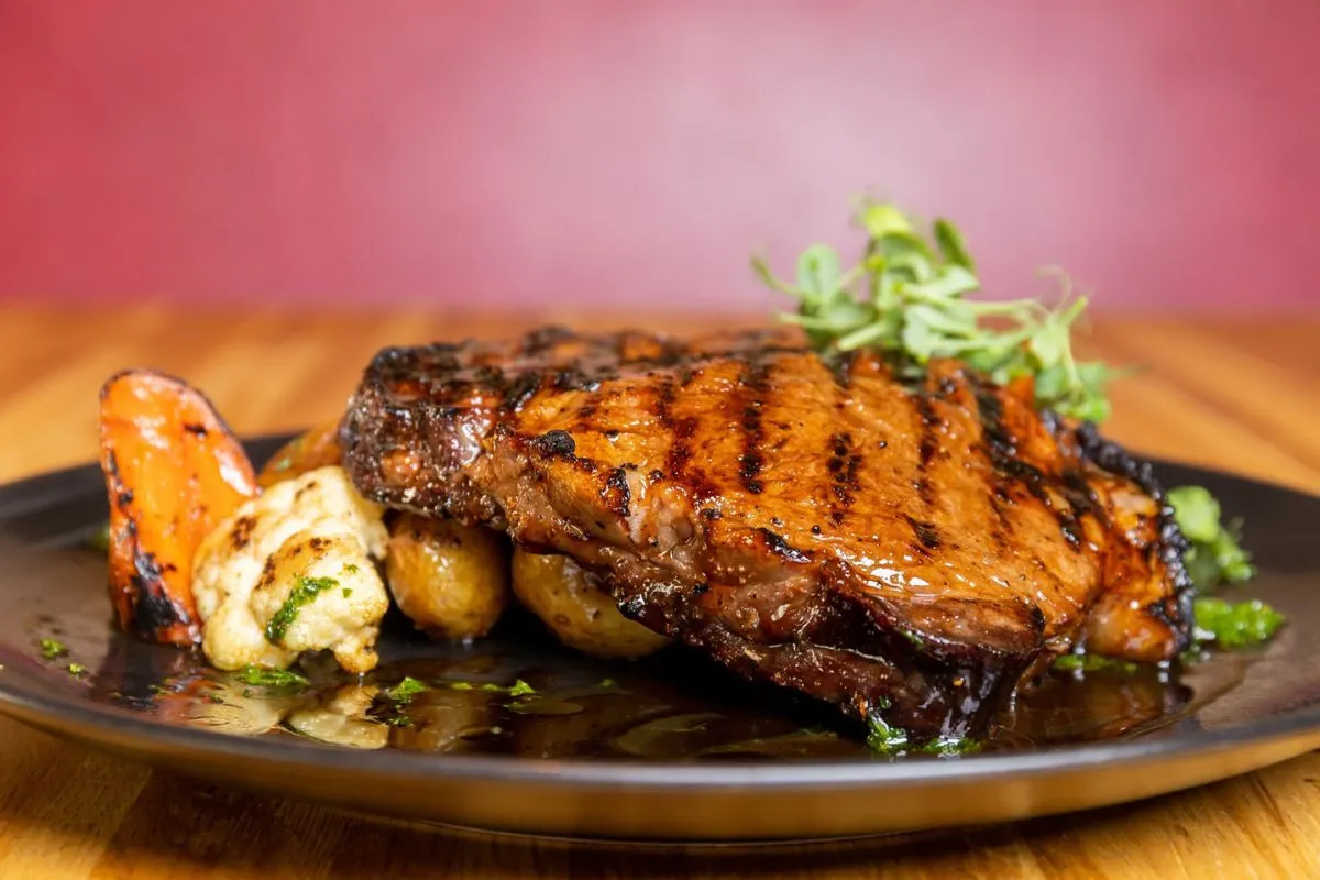 Grilled steak served with roasted potatoes and vegetables at Rub23.