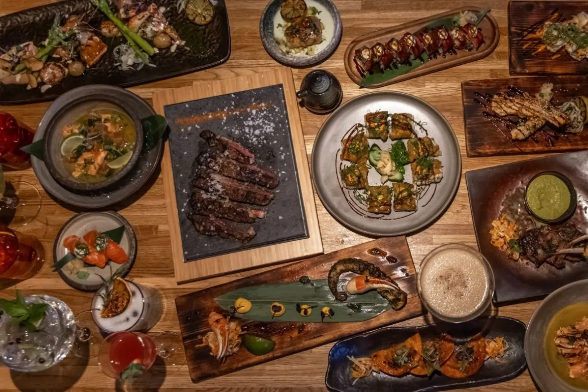 Overhead view of a table full of sushi, steaks, seafood, and cocktails at Rub23.