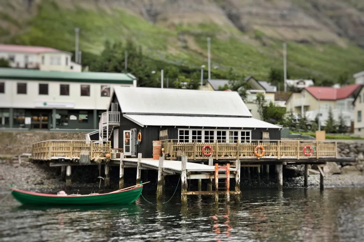 Exterior view of The Bait Shack waterfront restaurant on a pier with a green boat floating nearby.