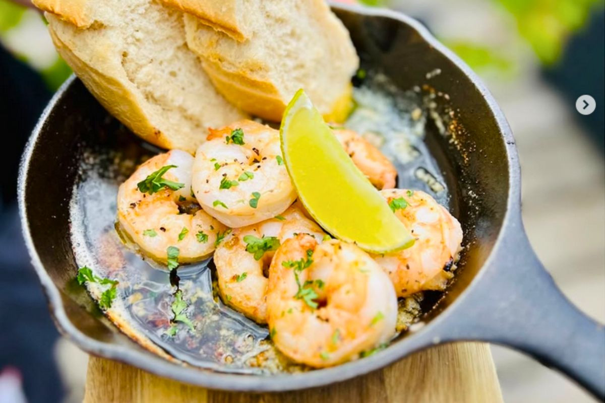 Garlic shrimp served in a hot cast-iron skillet with lime and bread at The Bait Shack.