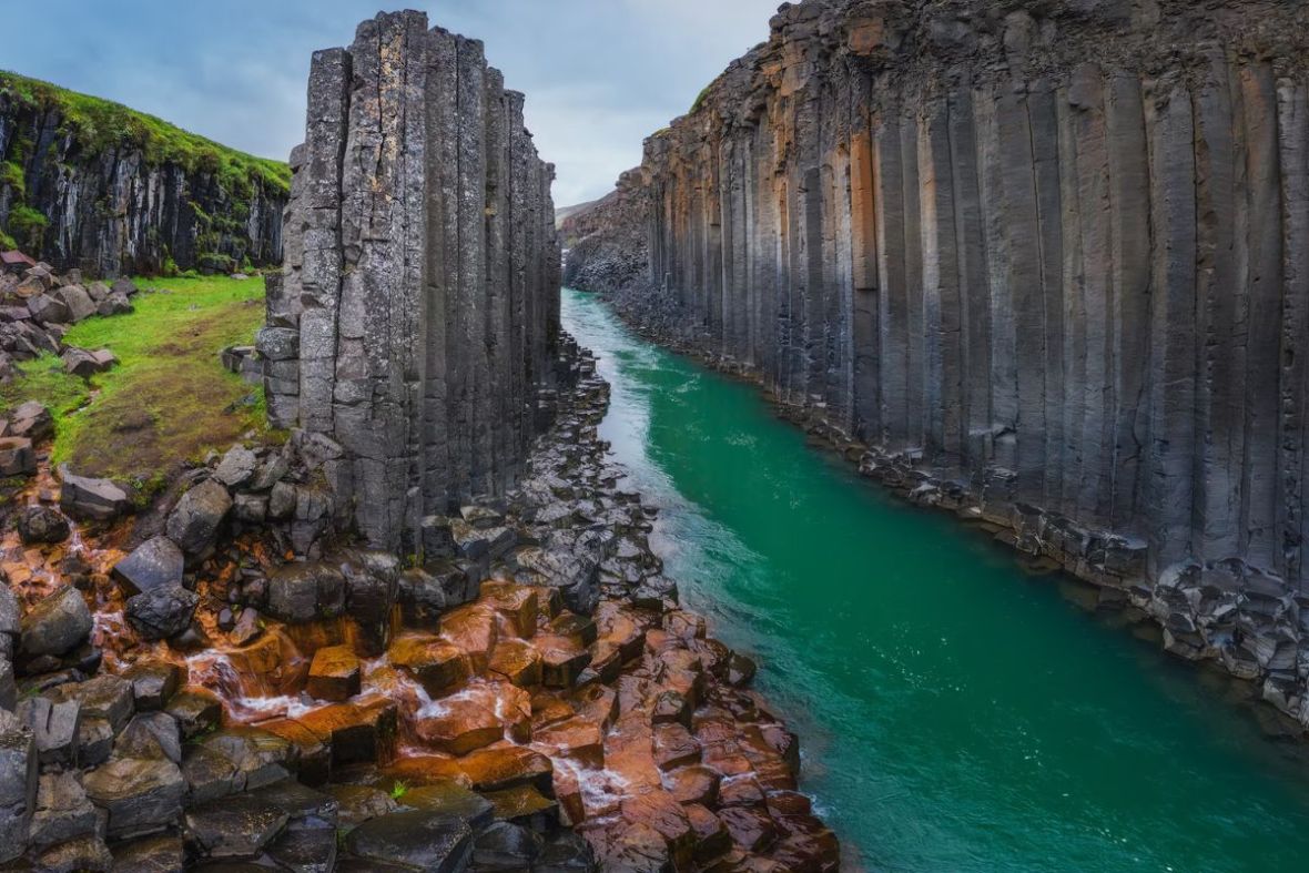 View of the turquoise waters flowing through the dramatic basalt columns of Stuðlagil Canyon with Tinna Adventure.