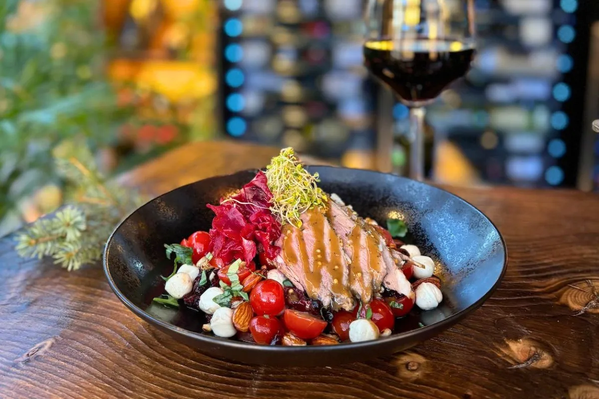 Gourmet sliced meat salad paired with a glass of red wine at Vínstofa Friðheima.